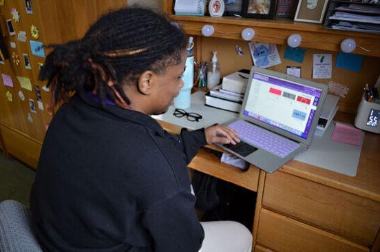 A female student works on a laptop in a dorm room